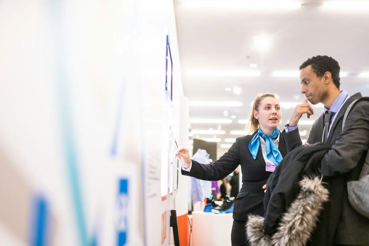 Two colleagues reviewing information together on a wall display