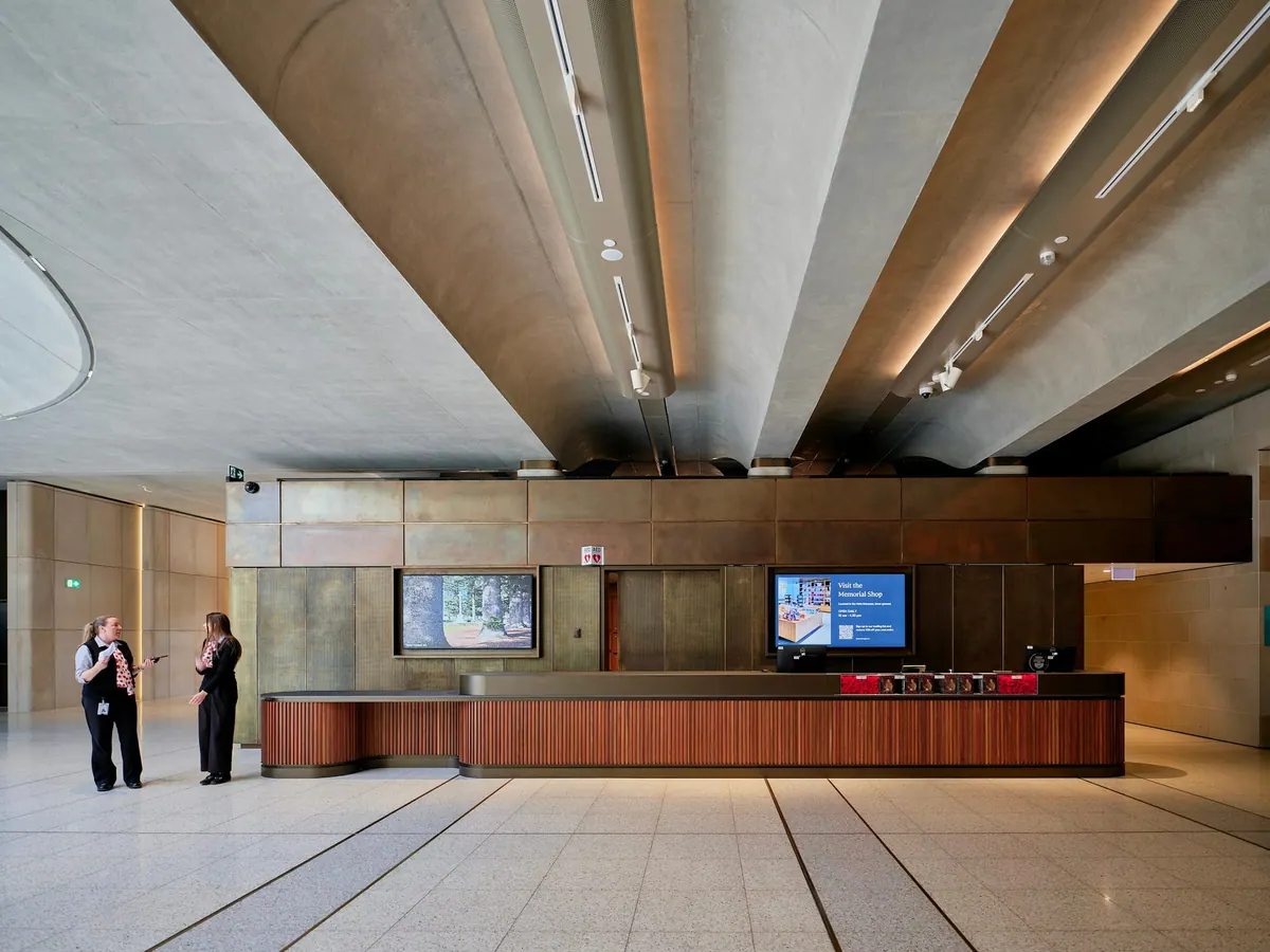 A bright, wood-panelled office lobby with two staff members at the front desk