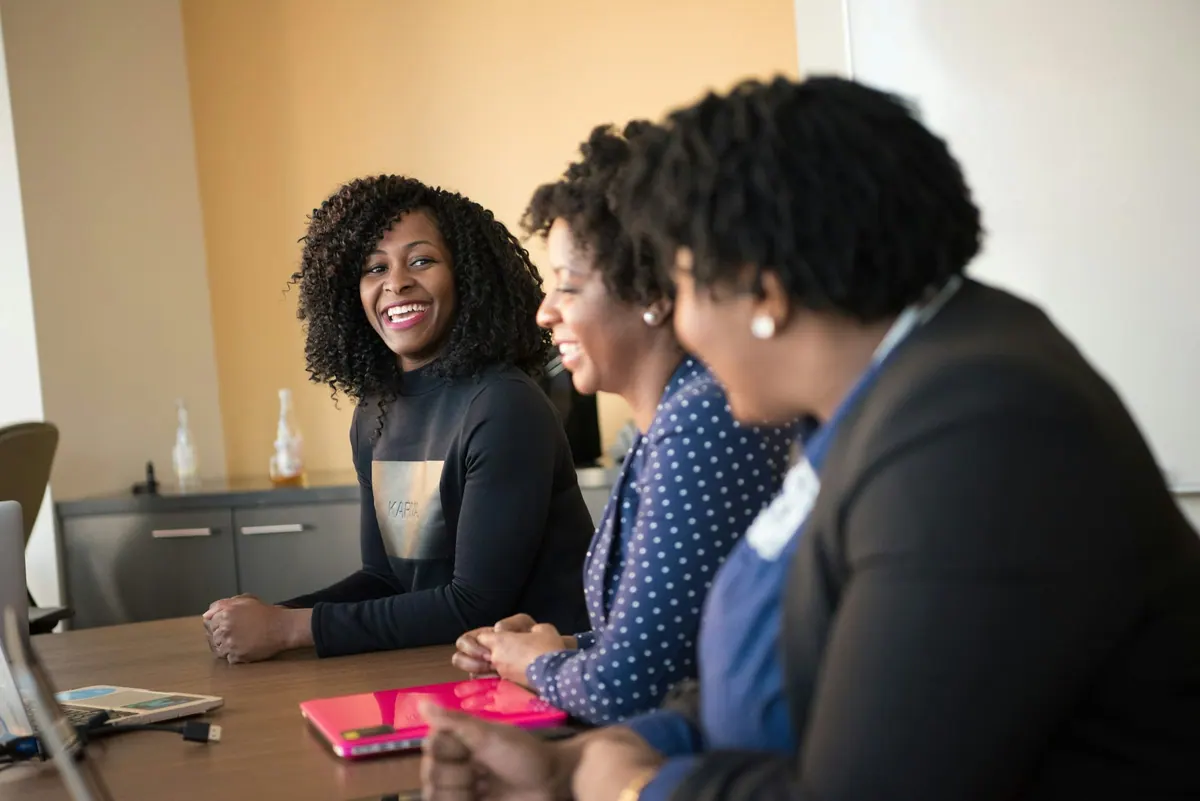 Three colleagues laughing together around a meeting table