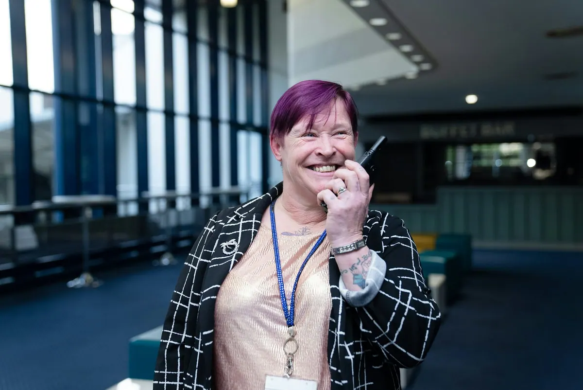 A smiling event coordinator speaking into a two-way radio