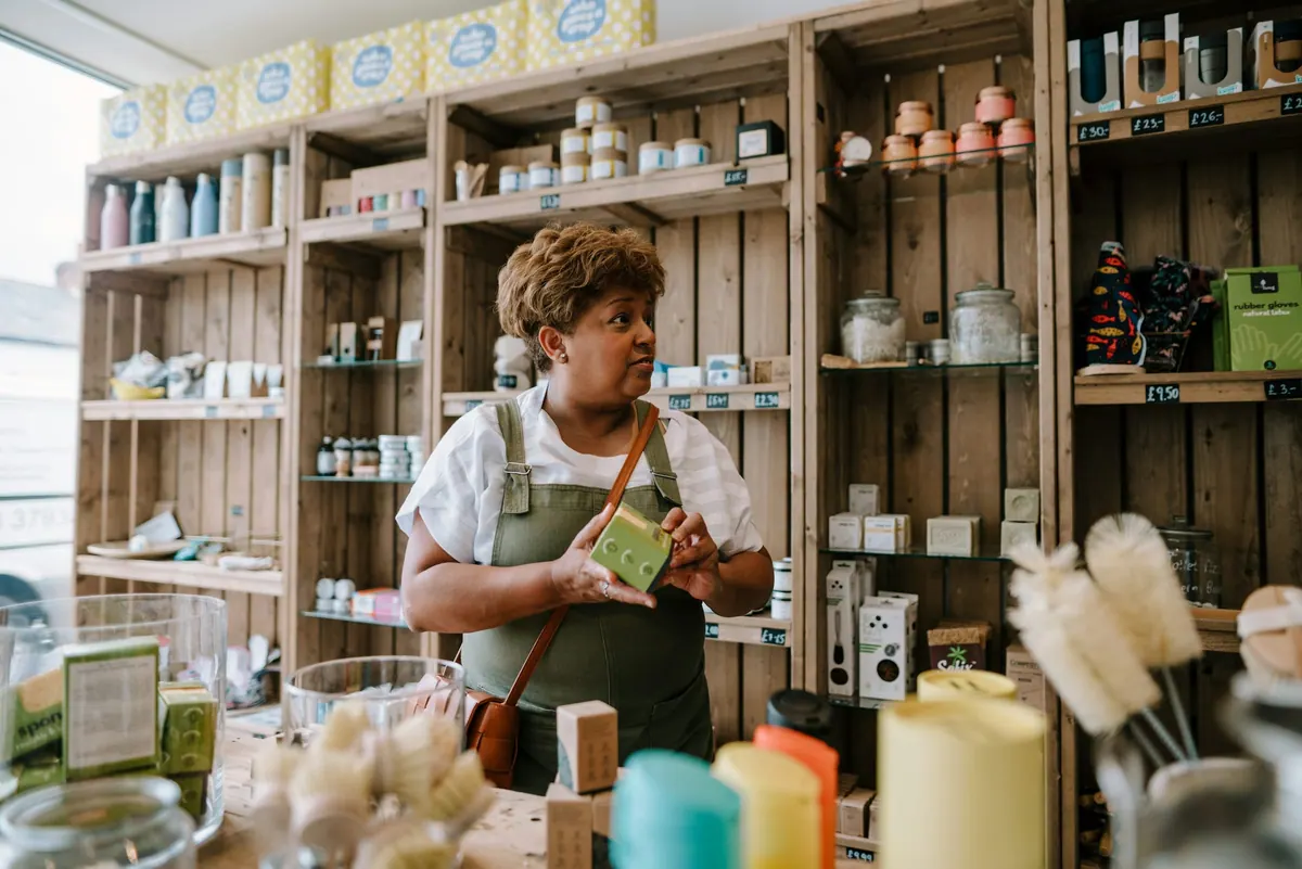 A shop owner talking with a customer among wooden shelves